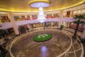 A hotel lobby with a central circular area featuring a fountain, surrounded by a marble floor with geometric patterns. - Puhua Hotel (Anshun)