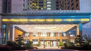 A modern hotel with a central atrium, large windows, and a covered entrance area. - Puhua Hotel (Anshun)