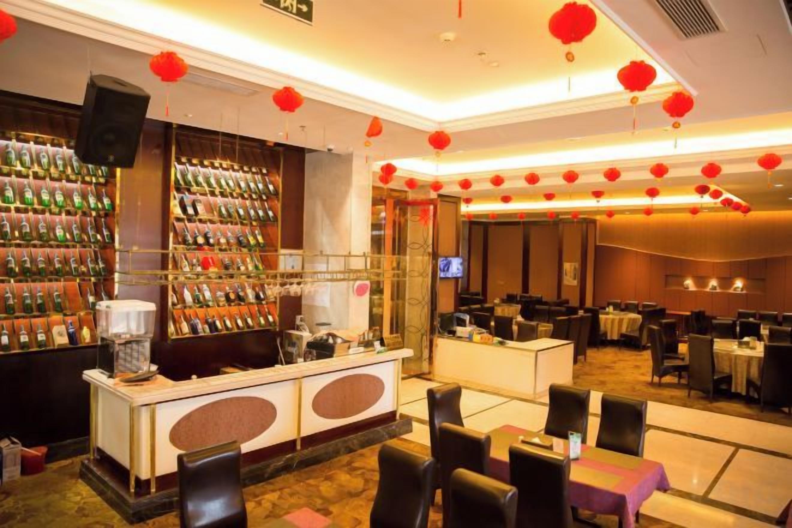 A hotel lobby with a reception desk, seating area, and a wall of liquor bottles.