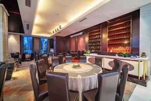 En moderne hotellobby med barområde, siddepladser og et stort bogreol.