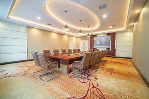 A conference room with a long table, chairs, a projector screen, and a carpet with a floral pattern. - Puhua Hotel (Anshun)