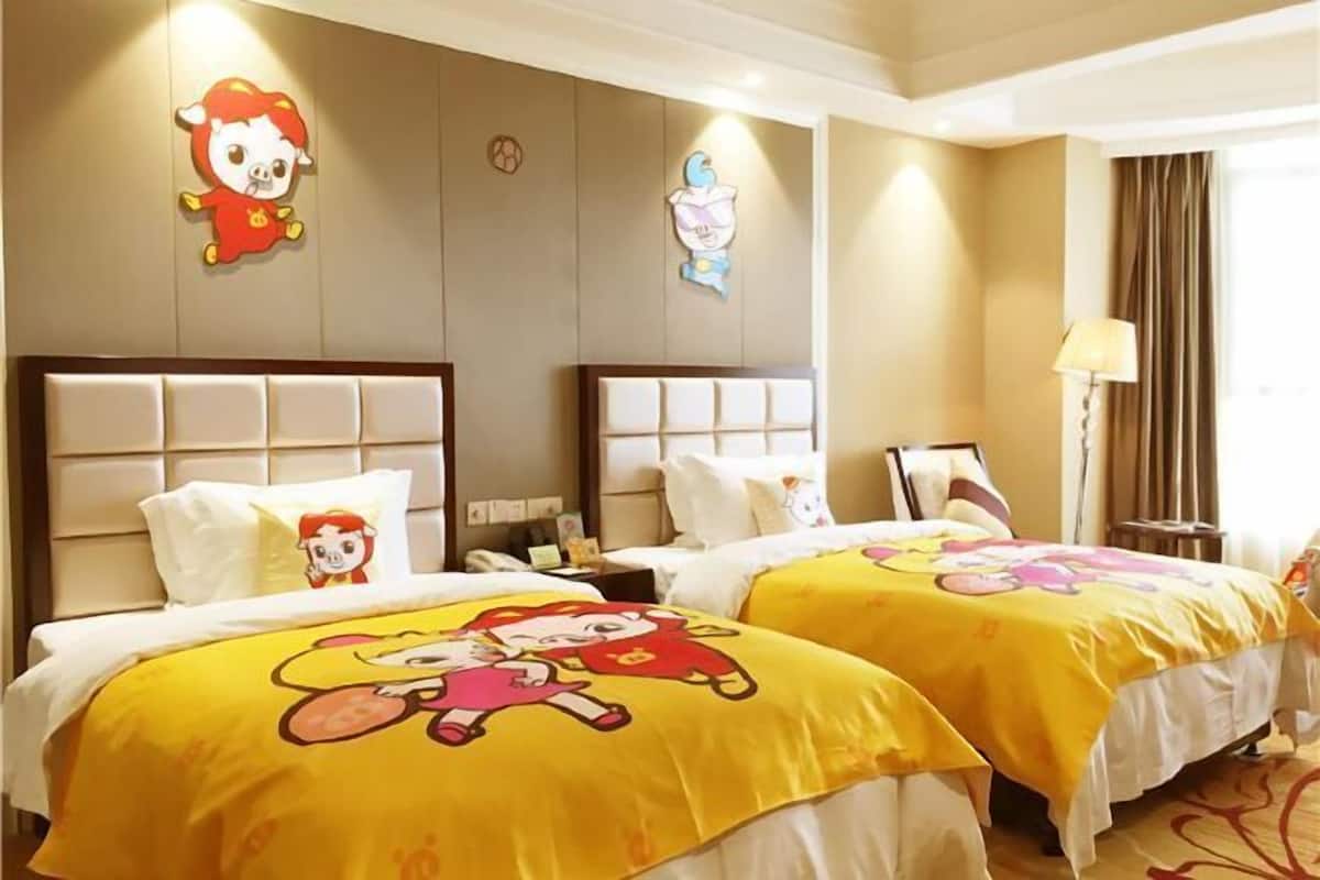 A hotel room with two beds, each with a cartoon character bedspread, a headboard, and a nightstand with a lamp.
