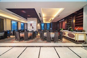 A hotel dining area with round tables and chairs, a reception desk, and a wine rack. - Puhua Hotel (Anshun)