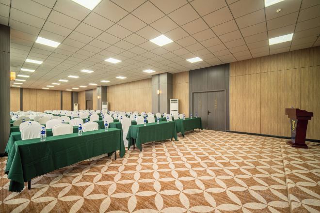 Un salón de conferencias con mesas dispuestas en filas, un atril y una alfombra estampada.