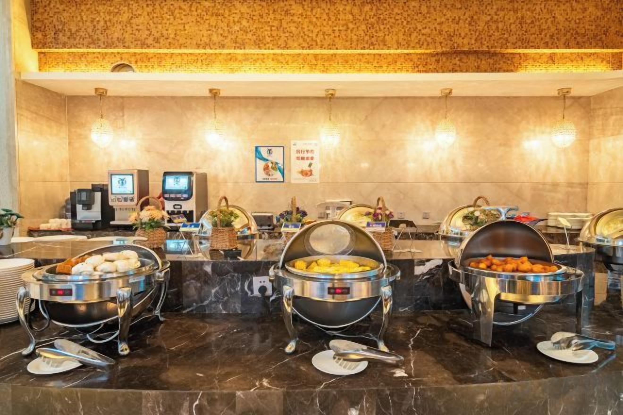 Un buffet avec plusieurs présentoirs de nourriture, un espace de réception doté d’un comptoir et un téléviseur fixé au mur.