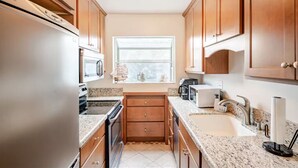 A compact kitchen with wooden cabinets, a built-in oven, a microwave, and a sink. - Stay in the Heart of Hillcrest! San Diego (San Diego)