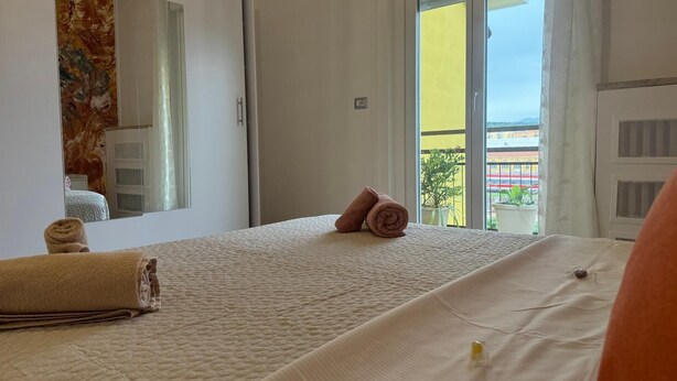 Une chambre d’hôtel avec un lit, un miroir et une vue sur un immeuble jaune, visible par la fenêtre.