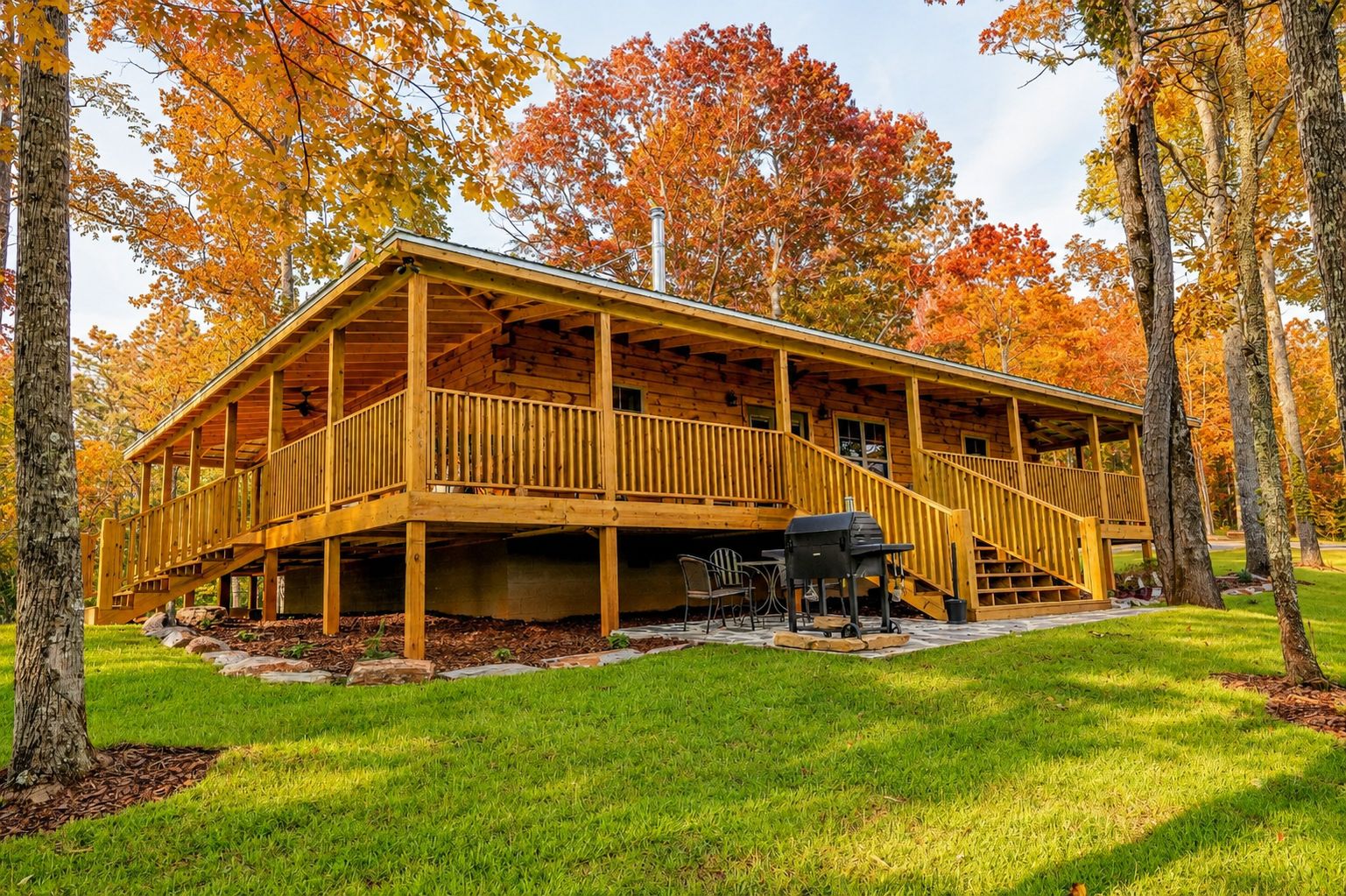 A wooden cabin with a covered deck, outdoor seating, and a grill area.