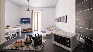 Un espace de vie compact comprenant un coin cuisine, un coin repas et un espace détente avec un canapé et un téléviseur.