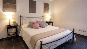 Une chambre à coucher bien rangée, avec un lit, des tables de chevet, des lampes et des climatiseurs fixés au mur.