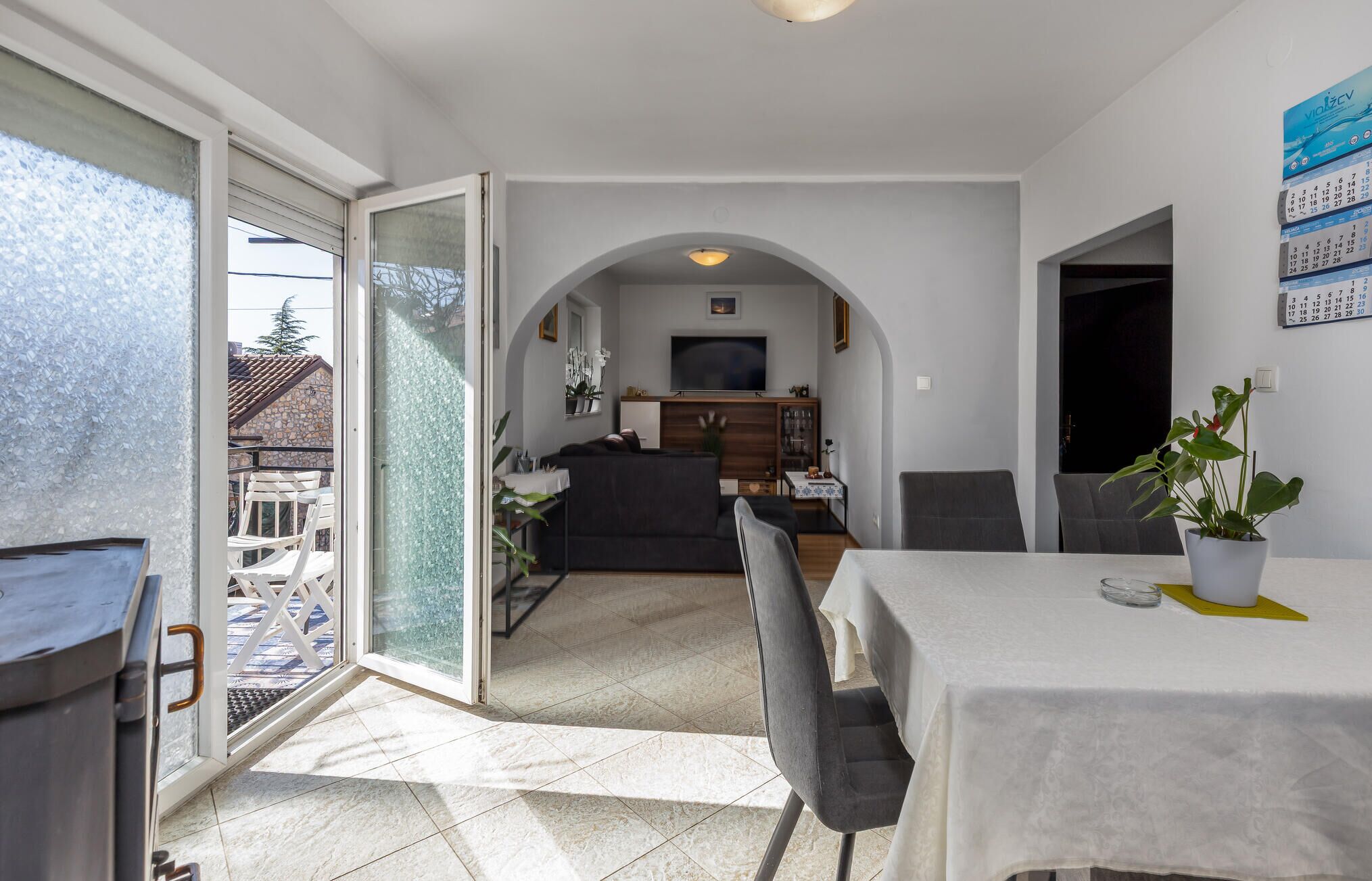 A modern living room with a sofa, TV, and dining area with chairs and a table.