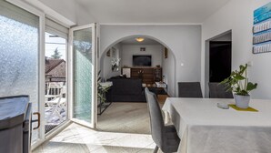 Un salon moderne comprenant un canapé, un téléviseur et un coin repas avec des chaises et une table.