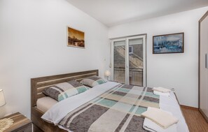 A bedroom with a bed, a nightstand, a lamp, and two paintings on the wall. - 2 bedroom awesome apartment in Novi Vinodolski (Novi Vinodolski)