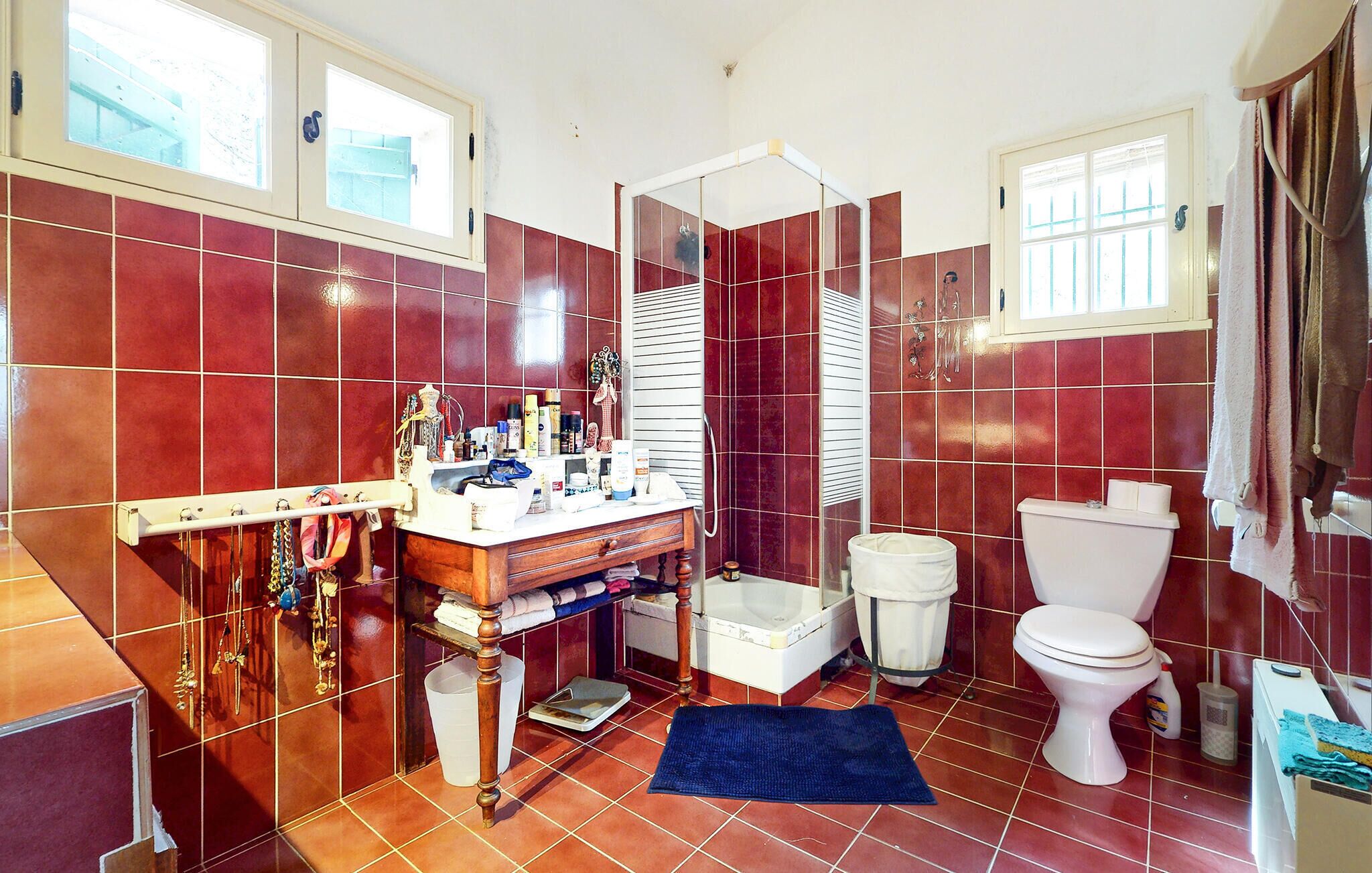 Un baño con baldosas rojas, un inodoro blanco, un lavabo blanco y una zona de ducha.