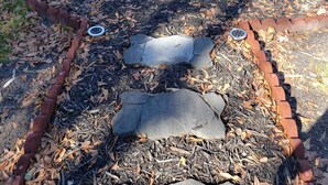 An outdoor seating area with wicker chairs and a table, surrounded by mulch and a brick border. - Close to everything-Centrally located to downtown, coliseum, hospital, & stadium (Fayetteville)