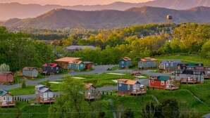 A residential area with small houses, a water tower, and mountains in the background. - The Lookout — Romantic Tiny Home w/ Mountain Views (Sevierville)