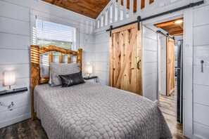 A bedroom with a large bed, wooden headboard, and a sliding barn-style door.