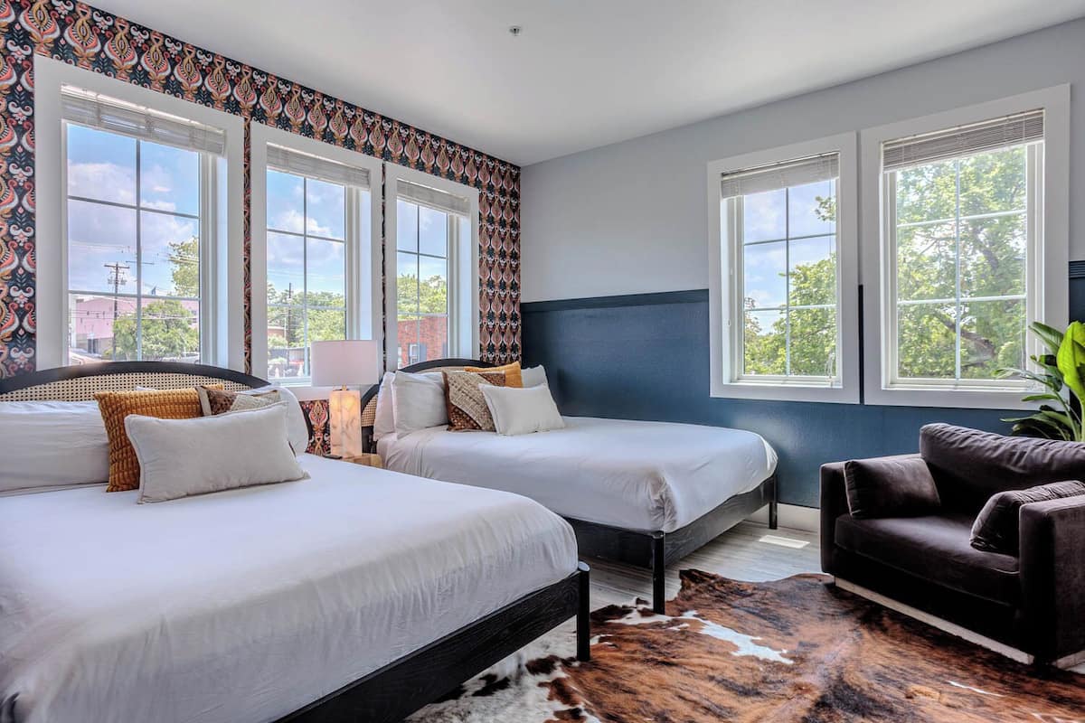 A hotel room with two beds, a sofa, and a cowhide rug.