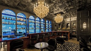 A bar area with a black and white patterned floor, multiple seating arrangements, and a chandelier. - Inn Cahoots (Austin)