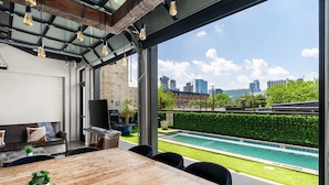 A modern outdoor dining area with a view of a swimming pool and city skyline. - Inn Cahoots (Austin)