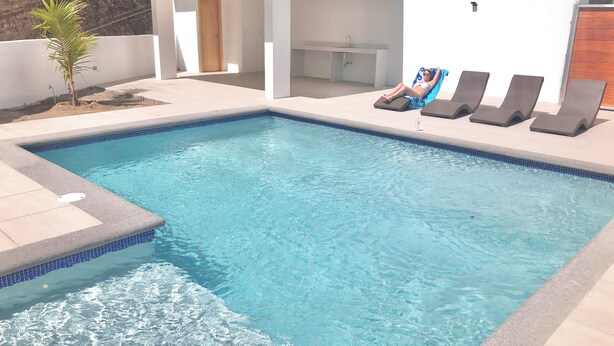 Piscina con sillas de descanso y una pequeña cocina.