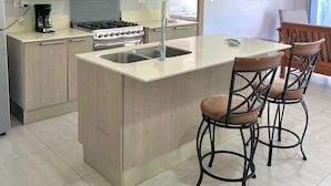Una cocina moderna con una isla central, electrodomésticos de acero inoxidable y armarios de madera.