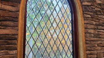Una ventana arqueada enmarcaada en piedra con vidrio de diseño en forma de rombos.