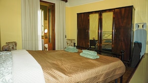 A hotel room with a large bed, a wardrobe, a mirror, and a chair. - La Casa Borgo Ischia di Castro (Ischia di Castro)