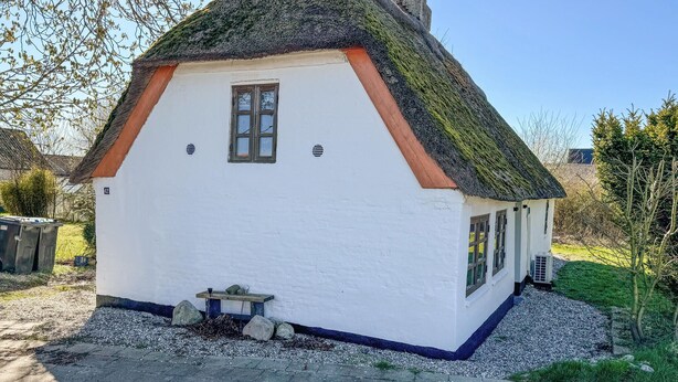 A small white house with a thatched roof, a window, and a small table outside. - Lovely home in Haderslev with WiFi (Haderslev)