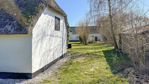 A narrow pathway leading to a white building with a thatched roof, surrounded by trees and a grassy area. - Lovely home in Haderslev with WiFi (Haderslev)