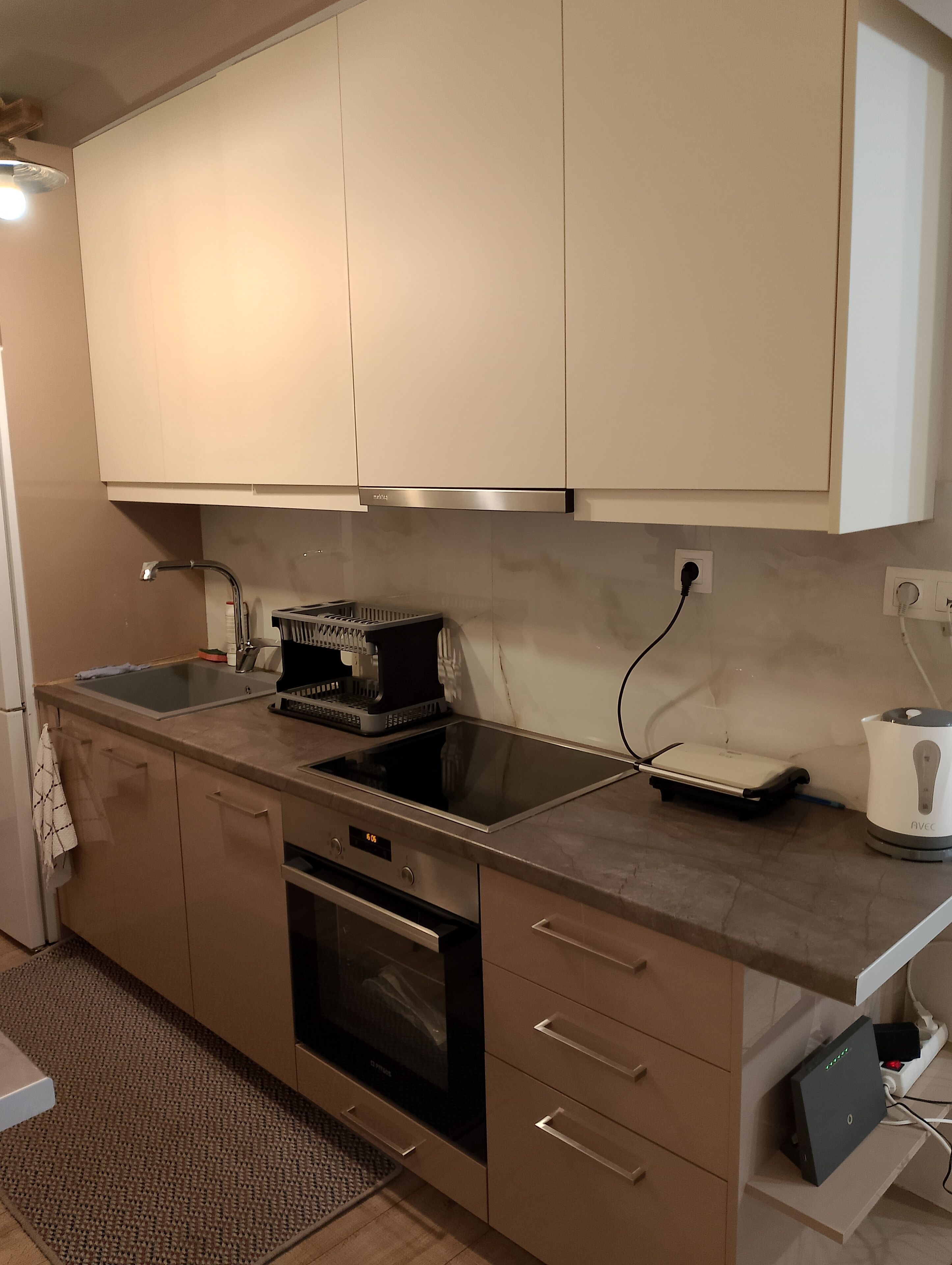 Una cocina moderna con electrodomésticos de acero inoxidable, horno empotrado y una encimera con cafetera y hervidor.