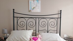 A bed with a metal headboard, white bedding, and a pink heart-shaped pillow. - Patisia Metro Station 2 bdrm apartment by MPS (Athina)