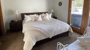 A bedroom with a bed, a nightstand, a lamp, a ceiling fan, and a window. - Charming 3-bedroom Sunriver house with WiFi, AC hot tub, bikes, kayak, grill (Sunriver)