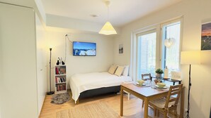 A bedroom with a bed, bedside table, and a TV on the wall. - Brand-new studio surrounded by forest, All New Cozy Home in Turku (Turku)