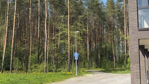 A gravel path leading to a building with a blue sign indicating a parking area. - Brand-new studio surrounded by forest, All New Cozy Home in Turku (Turku)