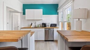 A modern kitchen with white cabinets, a teal accent wall, a dishwasher, and a microwave. - Historic Uptown w/2x Parking & Patio pet-friendly (St. Petersburg)