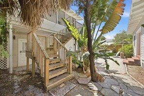 A wooden staircase leading to a porch with a view of a backyard.
