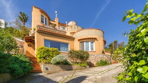 Una casa in stile mediterraneo con tetto curvo, ampie finestre e fondamenta in pietra.
