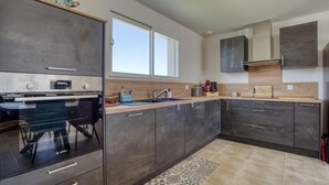 A modern kitchen with dark cabinets, a Bosch oven, a sink, and a window above the countertop. - Gorgeous home in Semussac (Semussac)