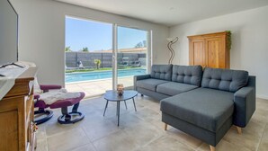 A modern living room with a grey sofa, a small round table, and a purple chair. A wooden cabinet and a plant are visible. - Gorgeous home in Semussac (Semussac)