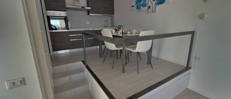 Cozinha moderna com área de jantar, e escada que leva a outro andar.