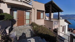 A modern building with a stone staircase leading to a wooden door, a balcony with a view of the sea, and a clear blue sky. - Eco-friendly design, modern comforts and a prime scenic location (Someraro)