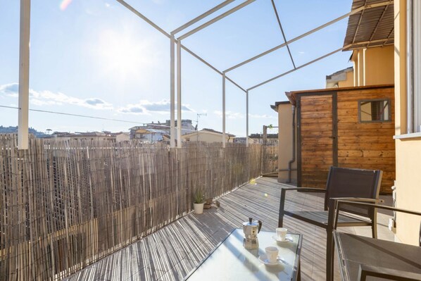 A balcony with a glass table, chairs, and a wooden fence.