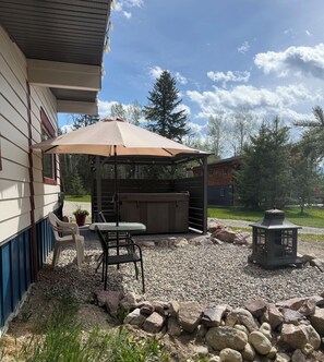 A patio with a table and chairs, a hot tub, and a lantern.