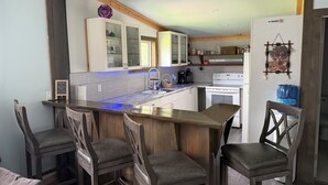 Una cocina moderna con barra, sillas de madera y un refrigerador blanco.