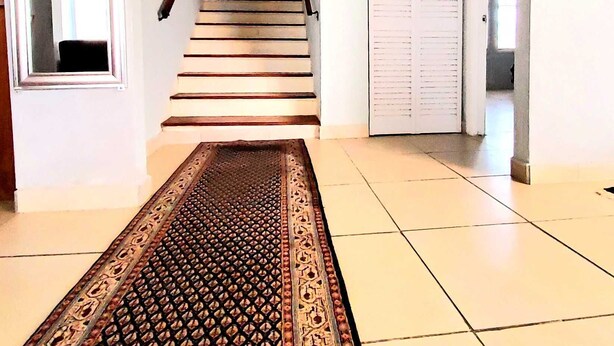 A hallway with a patterned carpet leading to a staircase. - Spacious & Expansive Miami Home With Free Parking (Homestead)
