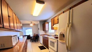 A kitchen with wooden cabinets, a white refrigerator, a microwave, and a stove. - Spacious & Expansive Miami Home With Free Parking (Homestead)