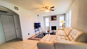 A living room with a beige sofa, a television, a fireplace, and a ceiling fan. - Spacious & Expansive Miami Home With Free Parking (Homestead)