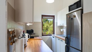 A modern kitchen with a wooden countertop, stainless steel appliances, and a window with a view of greenery.