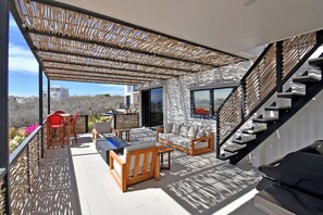 Enjoy the serene views from this outdoor living space, featuring a comfortable seating area and staircase leading to an upper level.